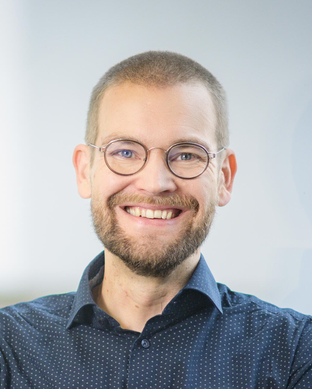 Eetu Niemi, kirjailija ja konsultti Hymyilevä mies, jolla on silmälasit, parta ja lyhyeksi leikattu tukka. Hänellä on tummansininen kauluspaita, ja taustana on vaalea seinä.